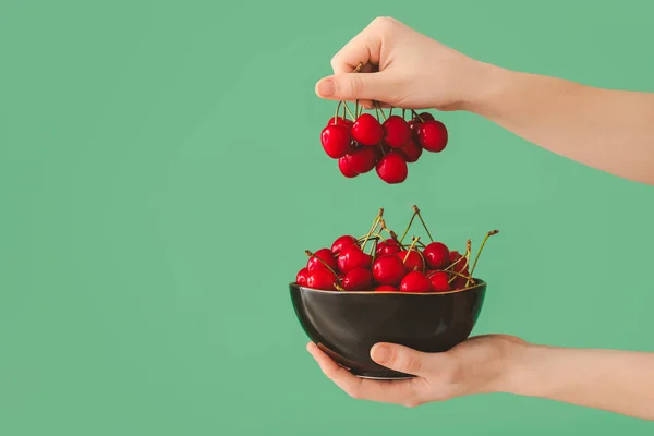 Woman with bowl of sweet cherry on color background