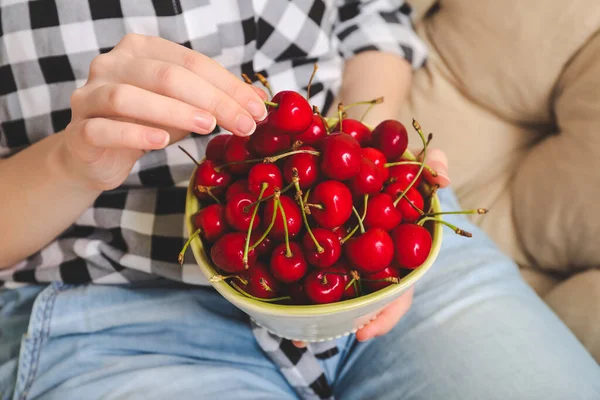 Woman eating sweet cherry at home