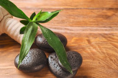 Ahşap arka planda bitki torbasıyla spa taşları