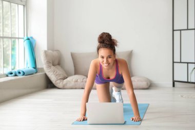 Evde dizüstü bilgisayar eğitimi alan genç bir bayan.