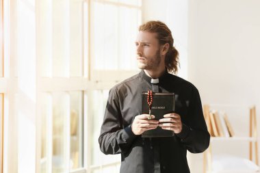 Evde İncil 'i olan bir erkek rahip.