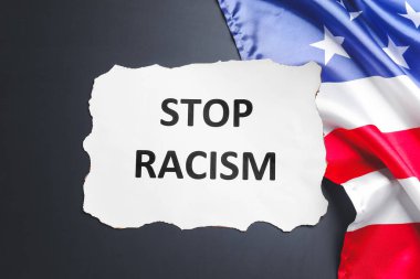 Koyu arkaplanda STOP RACISM ve ABD ulusal bayrağı yazılı kağıt