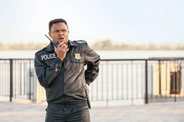 İki yönlü telsizi olan Afro-Amerikan polis memuru.