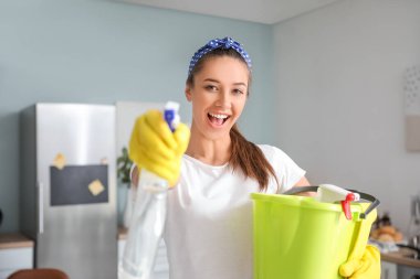 Mutfakta temizlik malzemesi olan genç bir kadın.