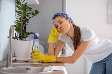 Mutfağı temizleyen üzgün genç kadın.