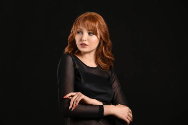 Koyu arkaplanda güzel kızıl saçlı bir kadın.