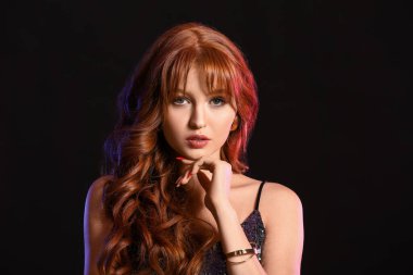 Koyu arkaplanda güzel kızıl saçlı bir kadın.