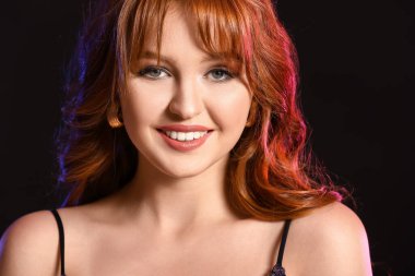 Koyu arkaplanda güzel kızıl saçlı bir kadın.