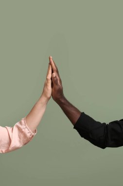 Beyaz kadın ve Afro-Amerikan erkeğin elleri, renkli arka planda birbirlerine beşlik çakıyor. Irkçılık kavramı