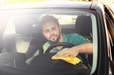 Adam içeride arabasını temizliyor.