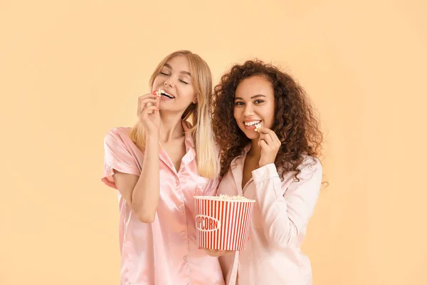 Όμορφες Νεαρές Γυναίκες Πιτζάμες Τρώνε Ποπ Κορν Στο Φόντο Χρώμα — Φωτογραφία Αρχείου