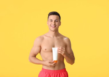 Arka planda güneş koruyucu kremi olan mutlu genç bir adam.