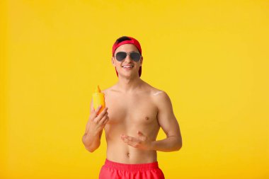 Arka planda güneş koruyucu kremi olan mutlu genç bir adam.