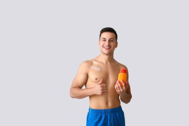 Işık arka planında güneş kremi olan mutlu genç adam.