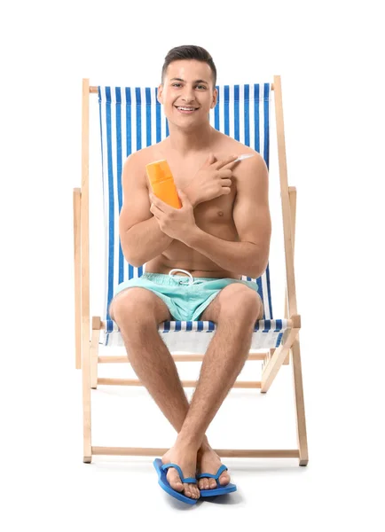 Happy young man with sun protection cream on white background