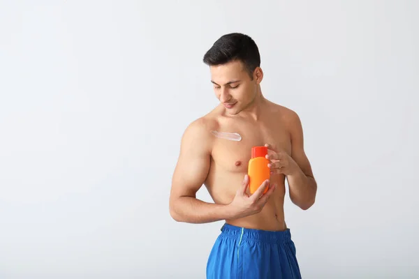 Glücklicher Junger Mann Mit Sonnenschutzcreme Auf Hellem Hintergrund — Stockfoto