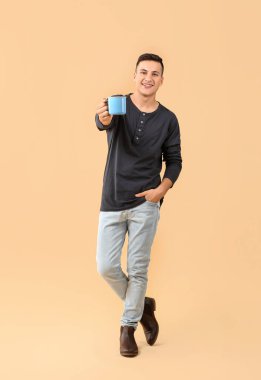 Arka planda çay fincanı olan yakışıklı genç adam.