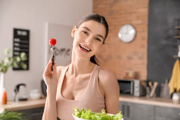 美しい若い女性は台所で野菜サラダを食べる — ストック写真