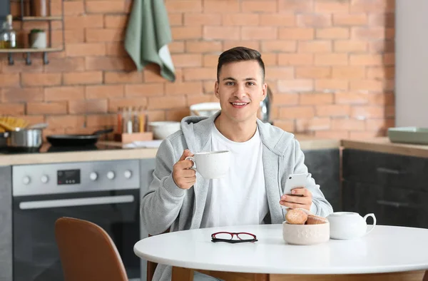 Evde Çay Içen Cep Telefonlu Yakışıklı Bir Genç — Stok fotoğraf