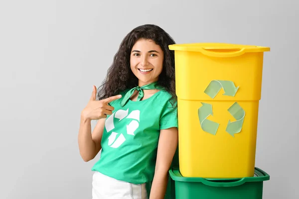 Woman dressed as eco superhero with trash bins on grey background