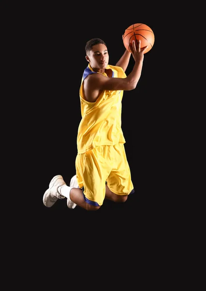 若いジャンプアフリカ系アメリカ人バスケットボール選手暗い背景に — ストック写真
