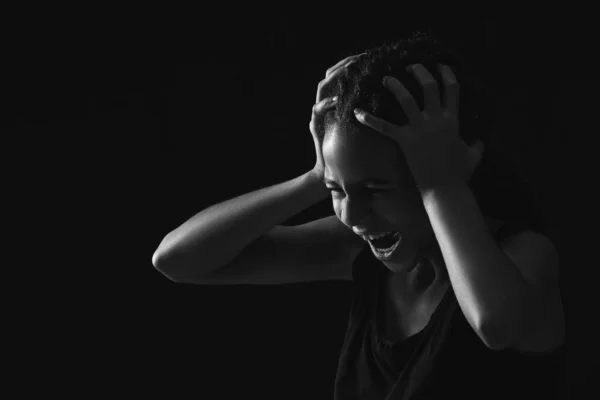 Stressed African-American girl on dark background. Stop racism