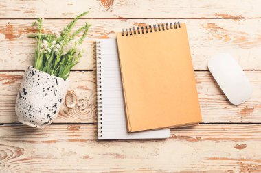 Bilgisayar fareli defterler ve beyaz ahşap arka planda çiçekler