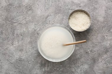 Gri zemin üzerinde pirinç ve su bulunan kaseler