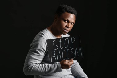 Siyah arka planda afişi olan üzgün bir Afro-Amerikalı. Irkçılığı bırak