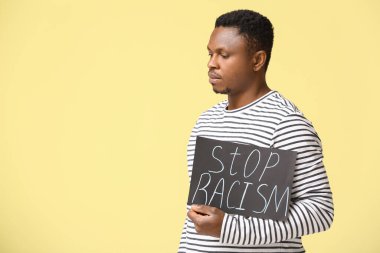 Arka planda afişi olan üzgün bir Afro-Amerikalı. Irkçılığı bırak