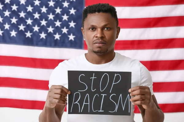 悲しいアフリカ系アメリカ人の男性は 米国の国旗の近くにポスターを貼っています 人種差別をやめ — ストック写真