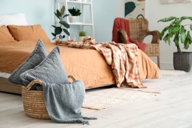 Yatak odasının içinde sepetin içinde yastıklar var.