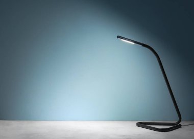 Karanlık odadaki masada parlayan lamba.