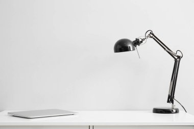 Lambalı dizüstü bilgisayar iş yerinde, ışık duvarının yanında.