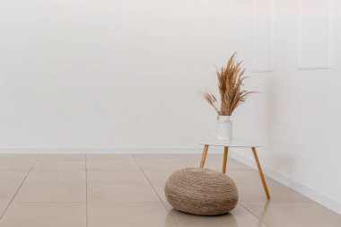 Çiçekli bir masa ve boş bir odada puf.