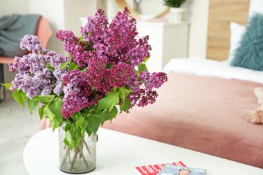 Yatak odasındaki masada güzel leylak çiçekleri olan vazo.