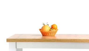 Mutfak masasında beyaz arka planda taze meyve dolu sepet.