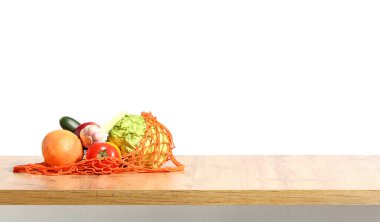 Mutfak masasında beyaz arka planda yeni ürünlerin olduğu bir alışveriş çantası.