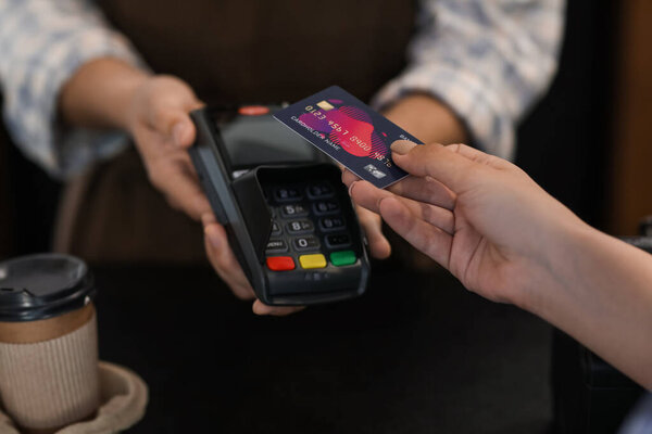 Customer paying for coffee via terminal in cafe, closeup