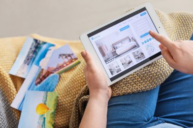 Evindeki otelde tablet bilgisayarlı rezervasyon odası olan kadın.