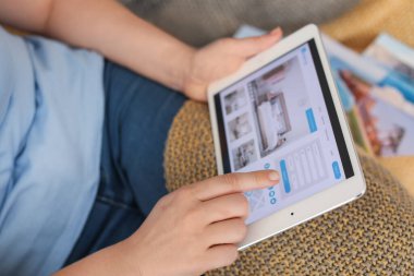 Evindeki otelde tablet bilgisayarlı rezervasyon odası olan kadın.