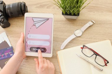 Tablet bilgisayarı olan bir kadın masada online bilet ayırtıyor.