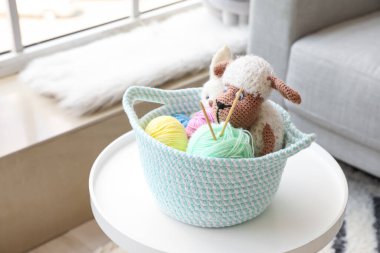 Masanın üzerinde oyuncak ve örgü iplikleriyle dolu bir sepet.