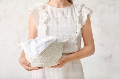 Hasır sepetli, arka planında havlu olan bir kadın.