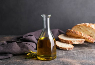 Koyu arkaplanda bir şişe lezzetli zeytinyağı ve ekmek.