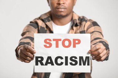 Arka planda afişi olan üzgün bir Afro-Amerikalı. Irkçılığı bırak