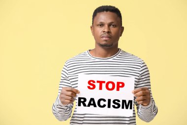 Arka planda afişi olan üzgün bir Afro-Amerikalı. Irkçılığı bırak
