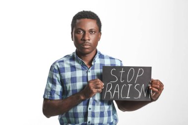 Beyaz arka planda afişi olan üzgün bir Afro-Amerikalı. Irkçılığı bırak