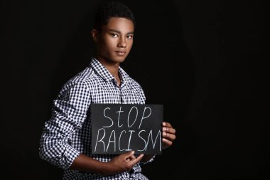 Siyah arka planda afişi olan üzgün Afro-Amerikalı genç bir çocuk. Irkçılığı bırak