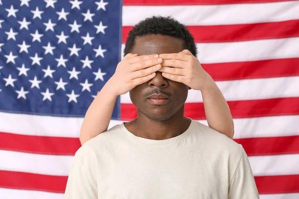 Ulusal bayrağın yanında üzgün Afro-Amerikan bir adamın gözlerini kapatan kişi. Irkçılığı bırak